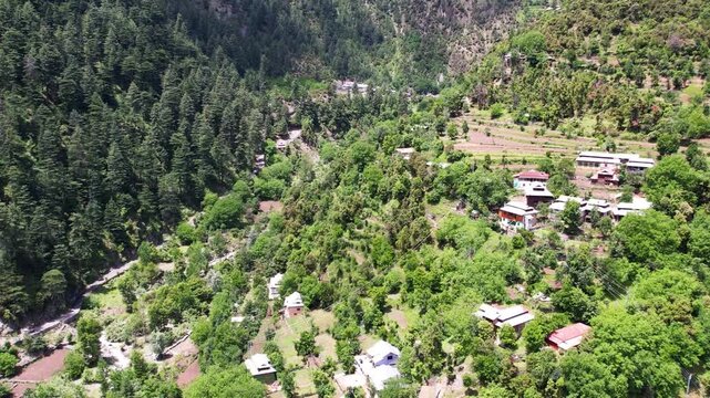 Village homes and cultivated slopes spread across a forested mountainside in Katha Piran, Kashmir, Pakistan