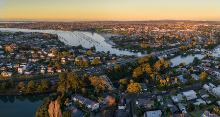Aerial view of the Panmure basin and Tamaki Estuary and surrounding suburbs in Auckland, New Zealand, at sunset. Numerous sailboats are anchored in the calm waters. © Zenstratus
