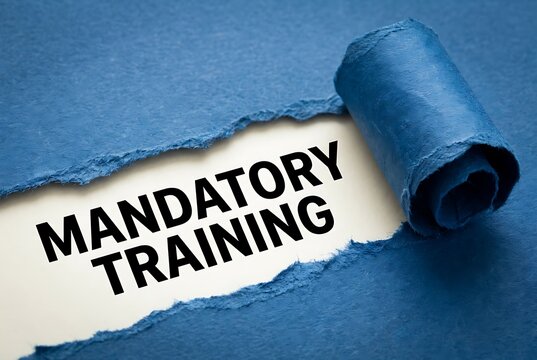 Torn blue paper reveals black text spelling mandatory training message for workplace compliance and professional development in corporate environments.