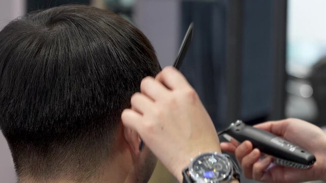 client getting a haircut with clippers in a professional barber shop setting over the shoulder perspective with focused grooming and clean background for personal grooming services.