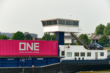 Inland container vessel with ONE cargo container and car crossing the Oude Maas river in Dordrecht Netherlands ocean network express Zuid Holland © VeugerStock