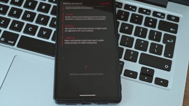 Smartphone screen displaying pandemic health advisory and emergency virus outbreak updates on a laptop keyboard background.