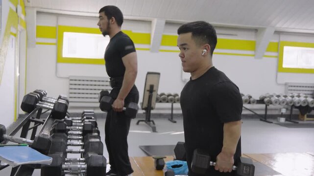 Young man with dwarfism doing lateral dumbbell raises workout in the gym