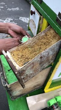 Street vendor preparing traditional Indonesian snack called "Kue Putu" in a wooden cart.