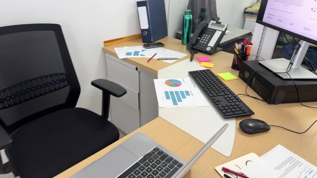 Empty office workstation with financial charts and laptop