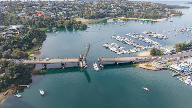 Aerial view of the Spit Bridge in Sydney, New South Wales, Australia, showing the bridge open for a boat, with a nearby marina filled with yachts and surrounding residential areas.