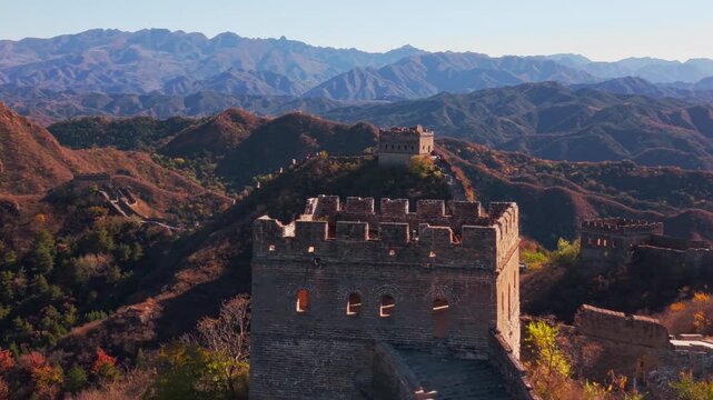 High angle view of the historic Great Wall of China winding across autumn hills with stone watchtowers under a clear blue sky
