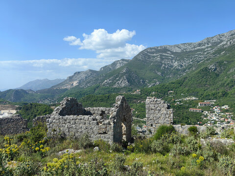 Haj Nehaj ruins stand on rocky hill above coastal Montenegrin valley with weathered stone walls, arched gateways and wild Mediterranean vegetation providing historical context and panoramic mountain