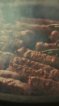 Smoking minced meat sausages grilling on a barbecue