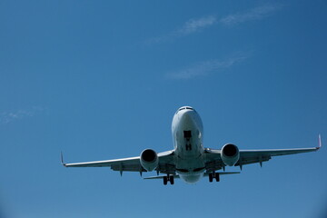 Fototapeta premium White passenger plane on final approach for landing against a blue sky