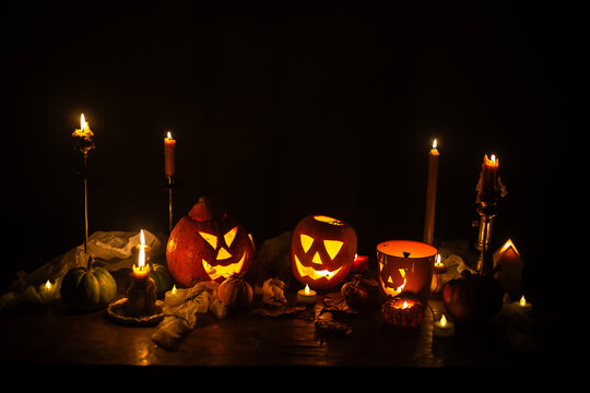 Happy Halloween. Carved glowing halloween pumpkins, burning candles and spooky spiders in dark. Atmospheric halloween night with jack o lantern decorations. Boo. holiday banner