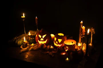 Jack o lantern glowing pumpkins, spooky spiders and burning candles on dark moody background. Happy Halloween. Spooky atmospheric halloween night, space for text. Trick or treat © sonyachny