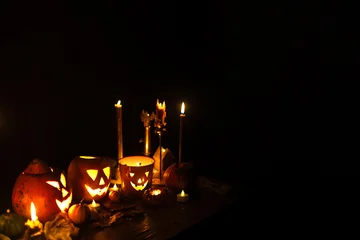 Happy Halloween. Jack o lantern glowing pumpkins, spooky spiders and burning candles on dark moody background. Spooky atmospheric halloween night, space for text. Trick or treat © sonyachny