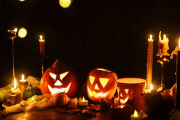 Jack o lantern glowing pumpkins, spooky spiders and burning candles on dark moody background. Happy Halloween. Spooky atmospheric halloween night, space for text. Trick or treat © sonyachny