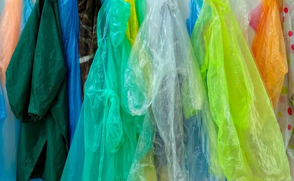 Close up of colorful plastic raincoats hanging in a row.