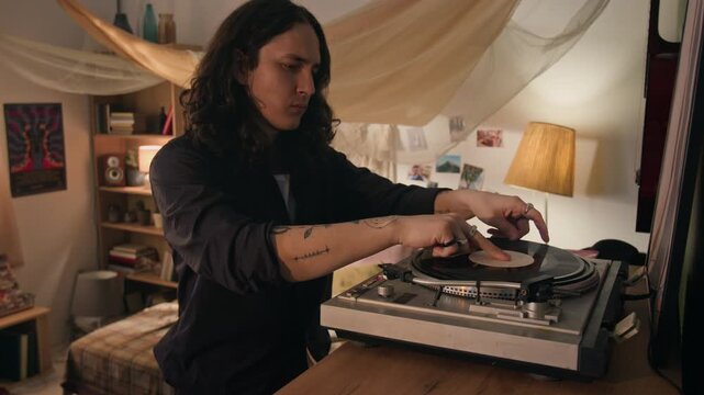 Young rocker with long hair taking vinyl record out of sleeve, placing it on vintage turntable, and starting playback. Footage for retro lifestyle and music app advertisements