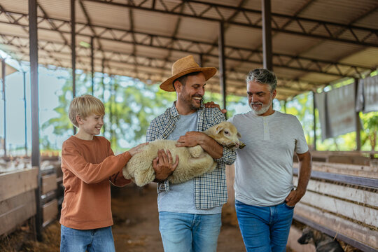 Multi generational family carrying a lamb on a farm
