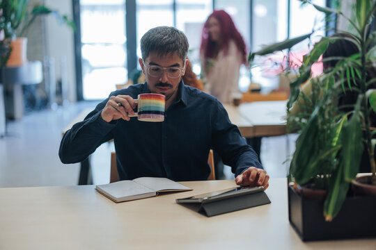 Man with LGBTQ plus mug working in modern office