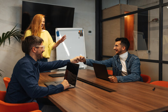 Business colleagues fist bumping achieving team success in meeting