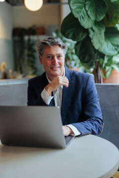 Mature businessman smiling while working on laptop