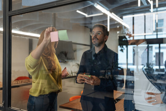Diverse business team brainstorming ideas on glass wall