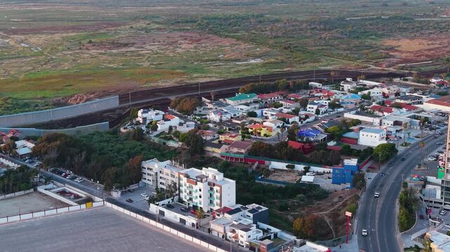 A striking high-angle drone sequence capturing the international border fence running parallel to a dense residential neighborhood.