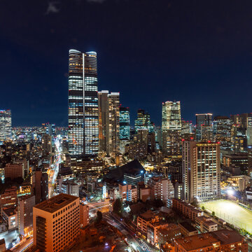 Aerial night view of the illuminated Tokyo cityscape and skyline with dense buildings.