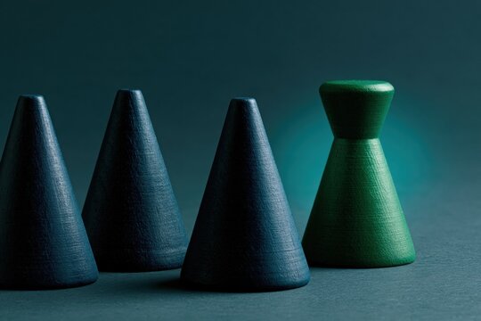 Green wooden pawn standing apart from dark blue cones for leadership concept background and teamwork poster design