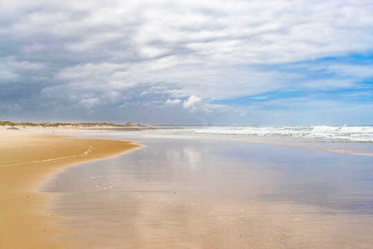 A serene, vast sandy beach under a dramatic cloudy sky evokes a sense of peaceful solitude. This beautiful coastal landscape with nobody is perfect for travel or wellness backgrounds.