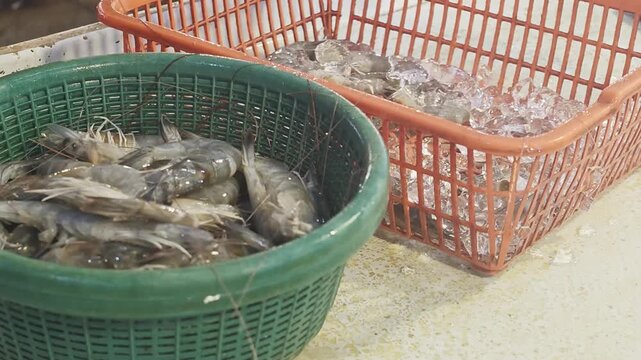 fresh raw prawns and clear ice cubes stored in plastic baskets at a seafood market stall targeting commercial restaurant supply campaigns grocery retail