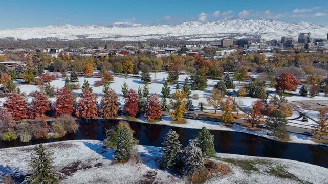 Ann Morrison Park Aerial View over Snow Covered Landscape Featuring Colorful Autumn Trees and Distant Snowy Mountains Drone Shot 4k