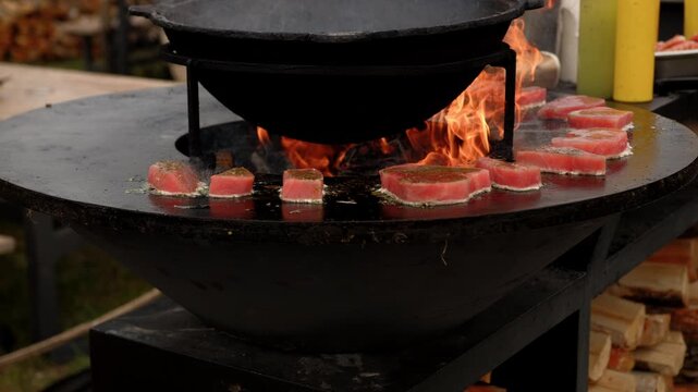Raw fish steak cooking on a rustic metal fire pit. Salmon fillet grilling over open flames in outdoor kitchen. Culinary process of preparation fresh seafood.