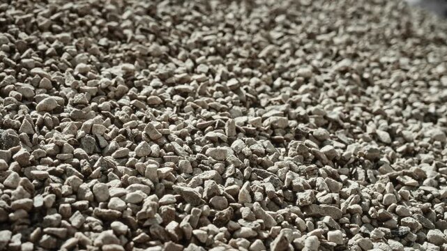 Low-angle close view of crushed stone aggregate pile for concrete production, showing rough texture, angular fragments, outdoor storage, industrial bulk and building material supply