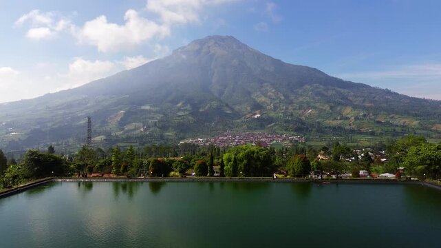 Aerial drone footage of Embung Kledung, a scenic artificial reservoir in Temanggung, Central Java, Indonesia, surrounded by the majestic Mount Sindoro and Mount Sumbing.