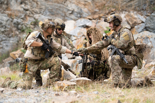 Team of military soldier army force having brief planning and hand unity for engage and rescue mission using map for actual field operation, peace and conflict resolution