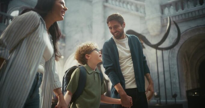 Natural History Museum Trip: Father Watches and Smiles as Mother and Young Son Explore Towering Mammoth Tusks, Family Learning About Ancient Creatures and Enjoying Fun Time Together.