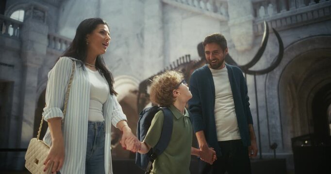 Natural History Museum: Cheerful Family of Three Waloks Through Grand Hall, Watching Dinosaur Fossils and Mammoth Tusks. Laught and Learn About Prehistoric Life Together. Slow Motion Portrait