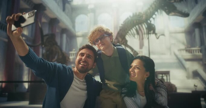 Natural History Museum: Cheerful Family Takes a Smartphone Selfie in Front of a Massive Dinosaur Fossil, Father, Mother and Young Child Smiling While Capturing Portrait to Share on Social Media