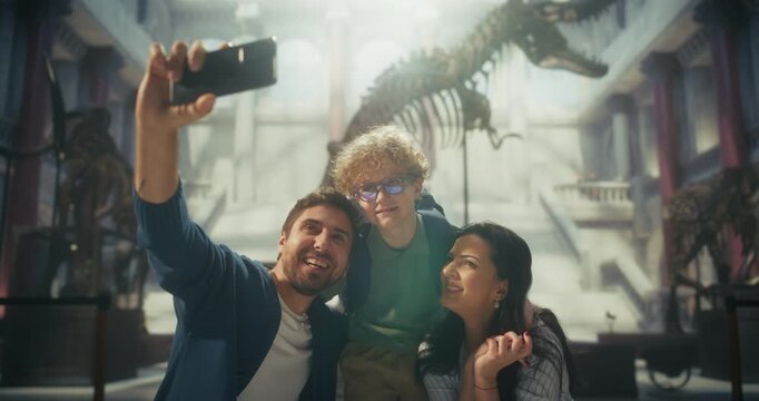 Natural History Museum: Happy Family Takes a Smartphone Selfie Beside a Dinosaur Skeleton, Father, Mother and Young Child Doing Potrait Picture for Social Media and Making Memories