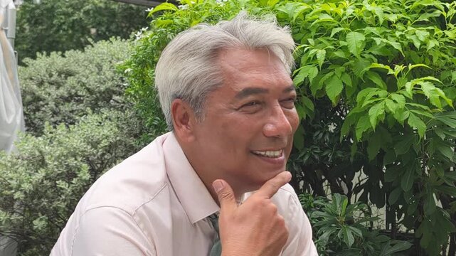 Old aged, senior business man thinking, planning with happy positive optimistic facial expression, green city outdoor scene