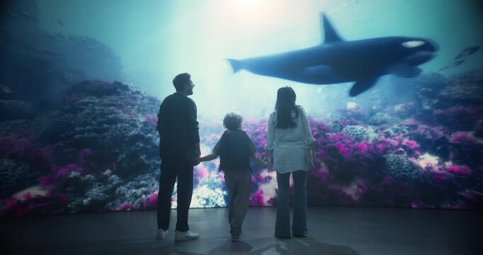 Oceanarium Marine Mammal Park Family of Three as Mom, Dad and Their Excited Son Stand Hand in Hand Watching an Orca Pass Above Pink Coral Reefs, Learning About Sea Creatures.