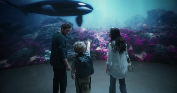 Oceanarium Marine Mammal Park: Cheerful Family Portrait as Mom, Dad and Their Young Son Point at a Swimming Orca, Watching and Learning About Marine Life and Ocean Life. Wide Shot Looking Around