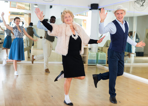 Senior woman and younger man dancing swing in studio