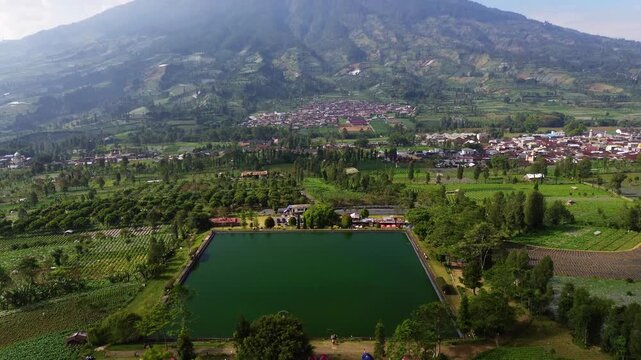 Aerial drone footage of Embung Kledung, a scenic artificial reservoir in Temanggung, Central Java, Indonesia, surrounded by the majestic Mount Sindoro and Mount Sumbing.