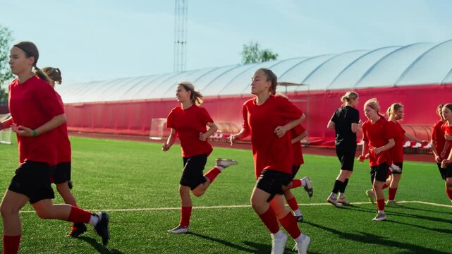 Womens soccer team conditioning on artificial turf field during high-intensity pregame training run, athletes in red uniforms building endurance and teamwork