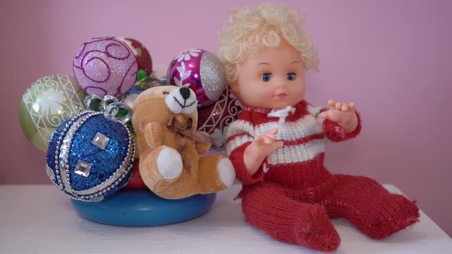 Vintage doll and teddy bear next to Christmas balls, Cute toy doll in red suit and Christmas decor