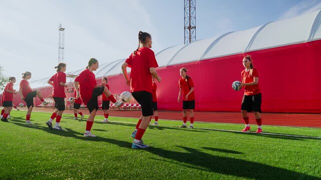 Intensive womens soccer training session with team passing drills on sunny artificial turf field, focusing on ball control, coordination, and cooperative warmup practice