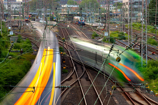 Railway lines at main station of Essen Germany with many lights, signals, catenary, glistening tracks, switches and trains in motion. Complex railway infrastructure technology at morning twilight.