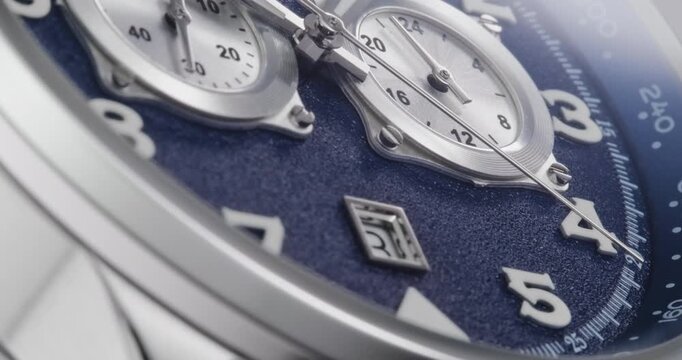 Macro close up of luxury chronograph wristwatch with blue textured dial and sweeping second hand