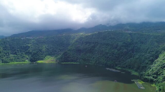 Aerial drone footage of Telaga Menjer, a beautiful volcanic lake located near the Dieng Plateau in Wonosobo, Central Java, Indonesia. Surrounded by lush green hills and spectacular mountain scenery
